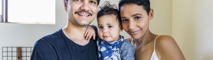 Aboriginal family of 3 with baby son, looking very content, in the middle of Mum and Dad