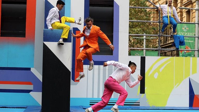 physical theatre - men in coloured suits jumping off colourful, outdoor set