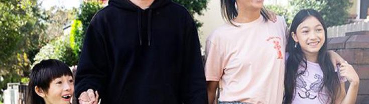 A family walking together on a suburban street.