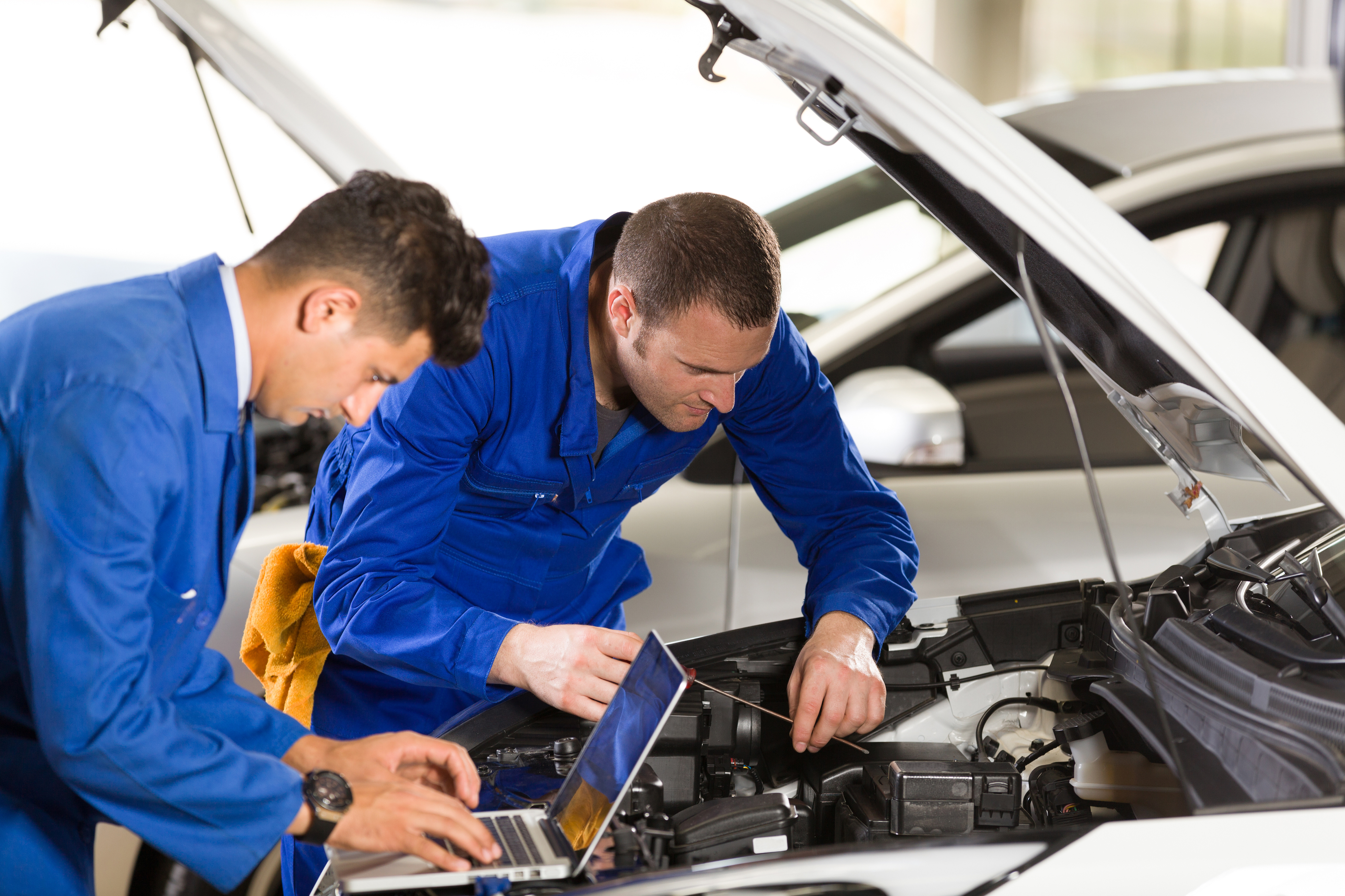 Image of two mechanics using a laptop to test a car's engine