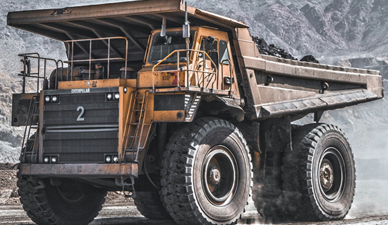 An imposing mining dump truck stands tall against a rugged landscape.