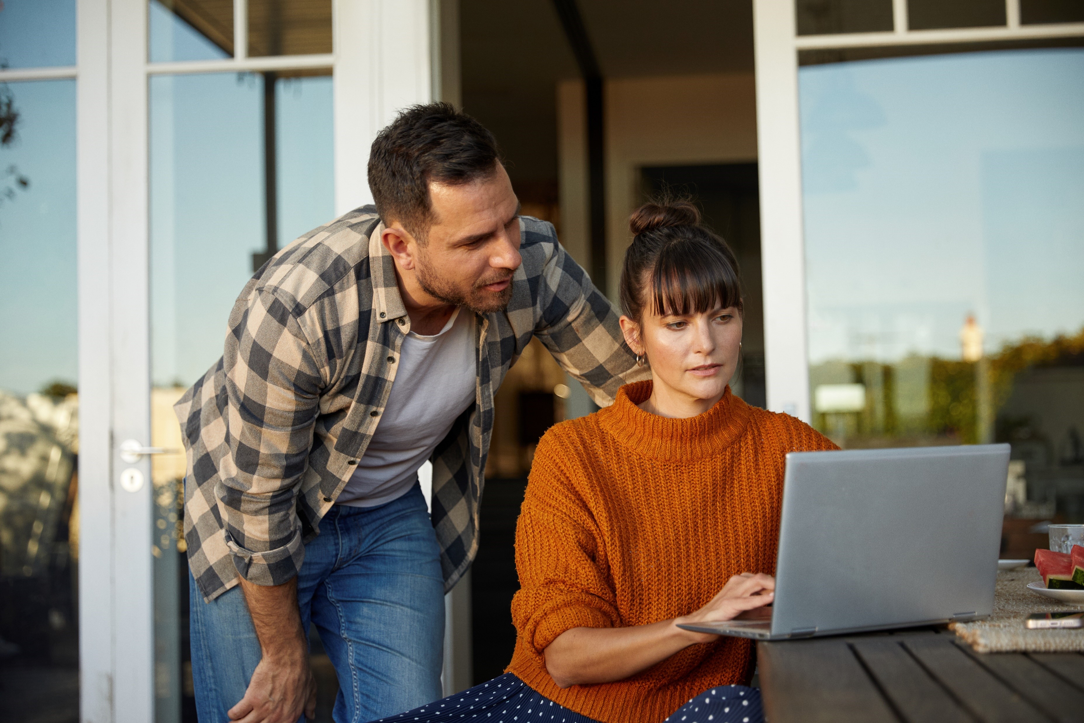 A couple outside working on a laptop together