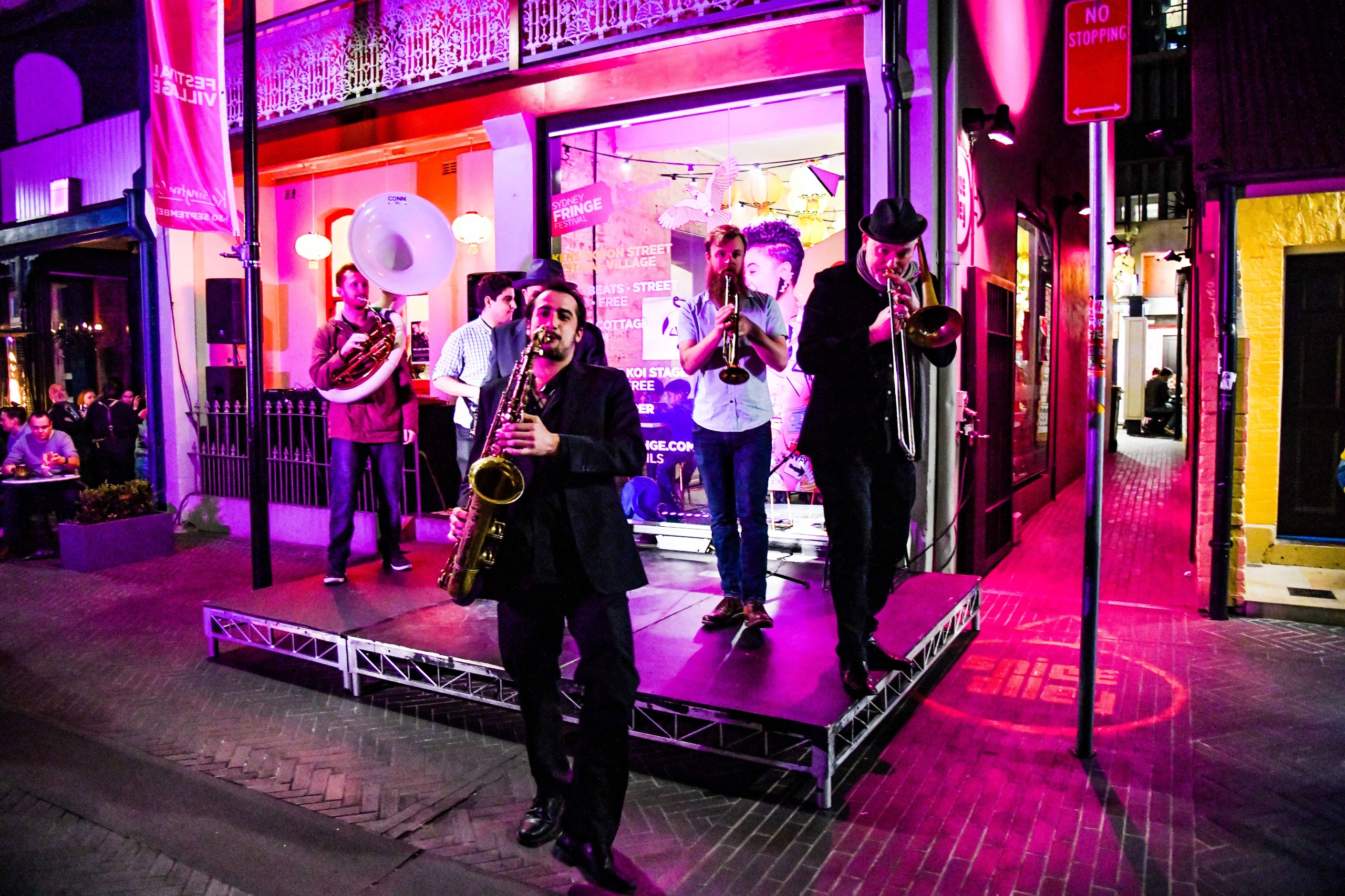 Five musicians performing on a small stage outside