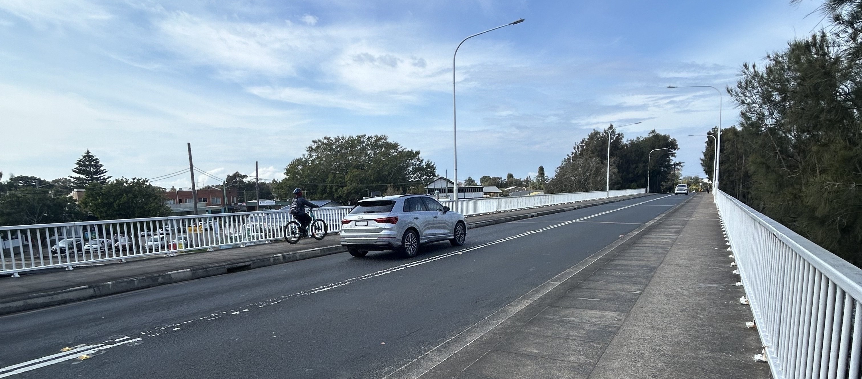 A silver car driving over a bridge 