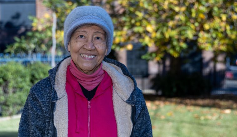 A senior woman standing in the park wearing winter clothes