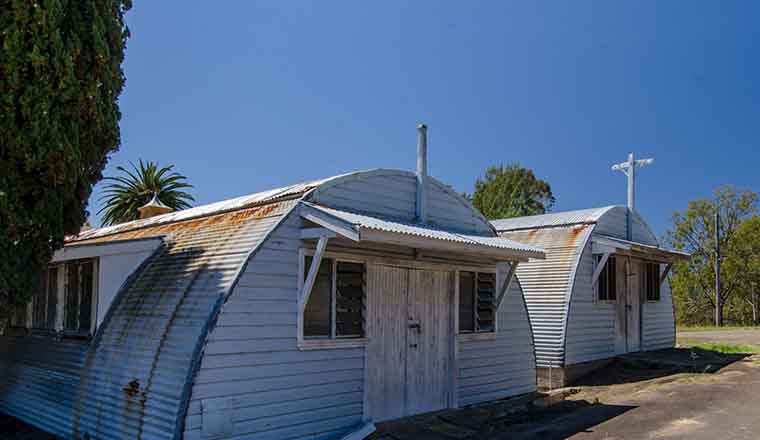 Two old Nissen huts, showing signs of age with rust and flaking paint