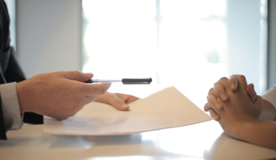 A male hand passing a piece of paper and pen to a female