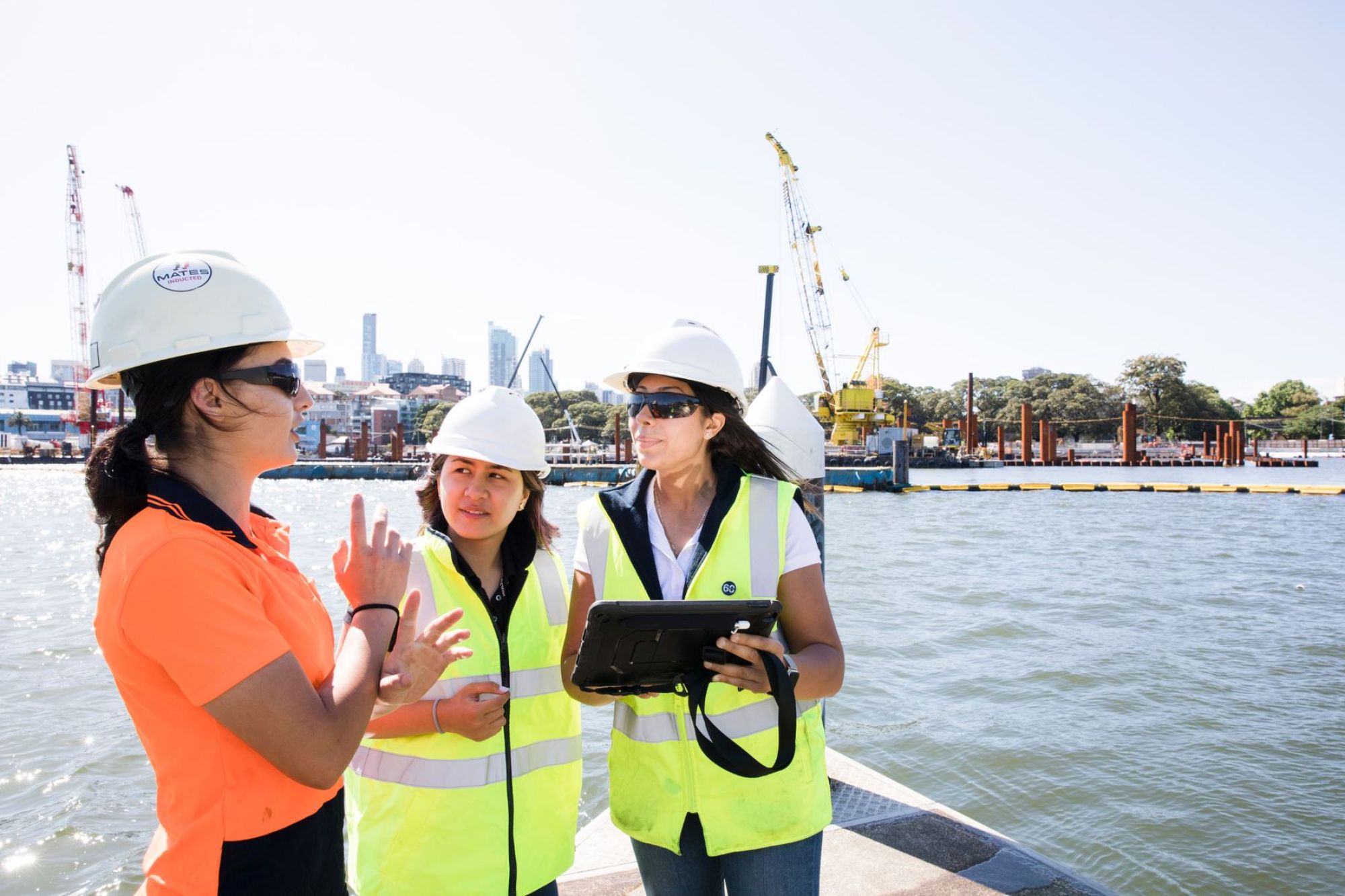 Women standing on a pontoon is hi-vis gear discussing plans.