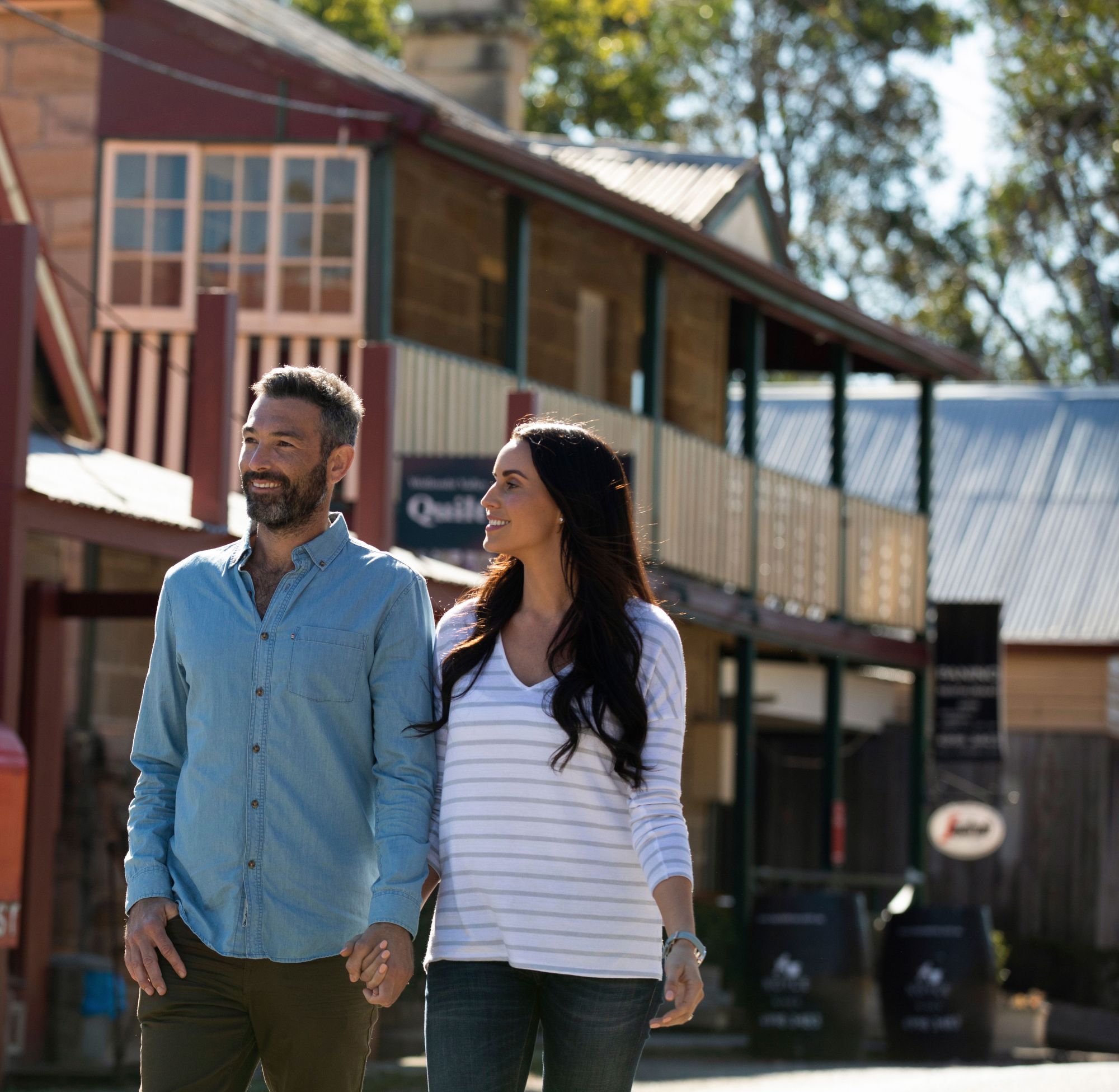 A couple walking down a wide street with a post box and heritage buildings in the background - Cropped tight