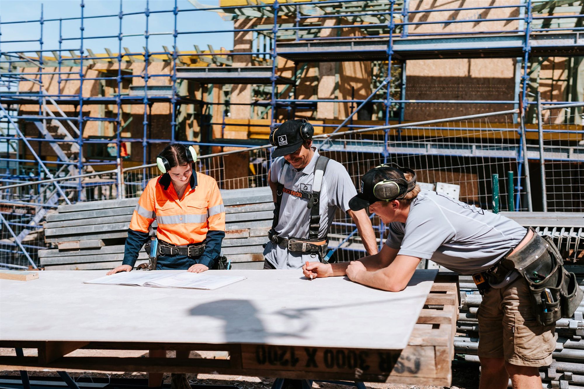 Ashlyn and 2 colleagues are standing on site reviewing a plan.