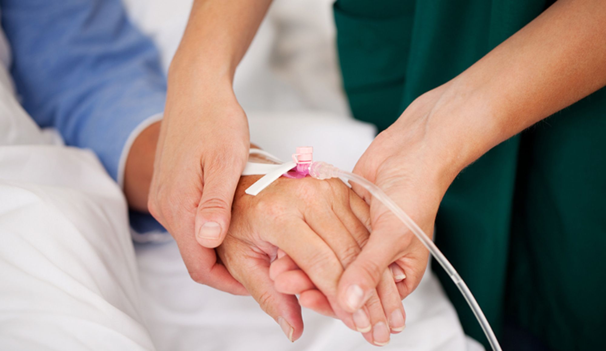 Closeup of nurse holding patients hand in hospital