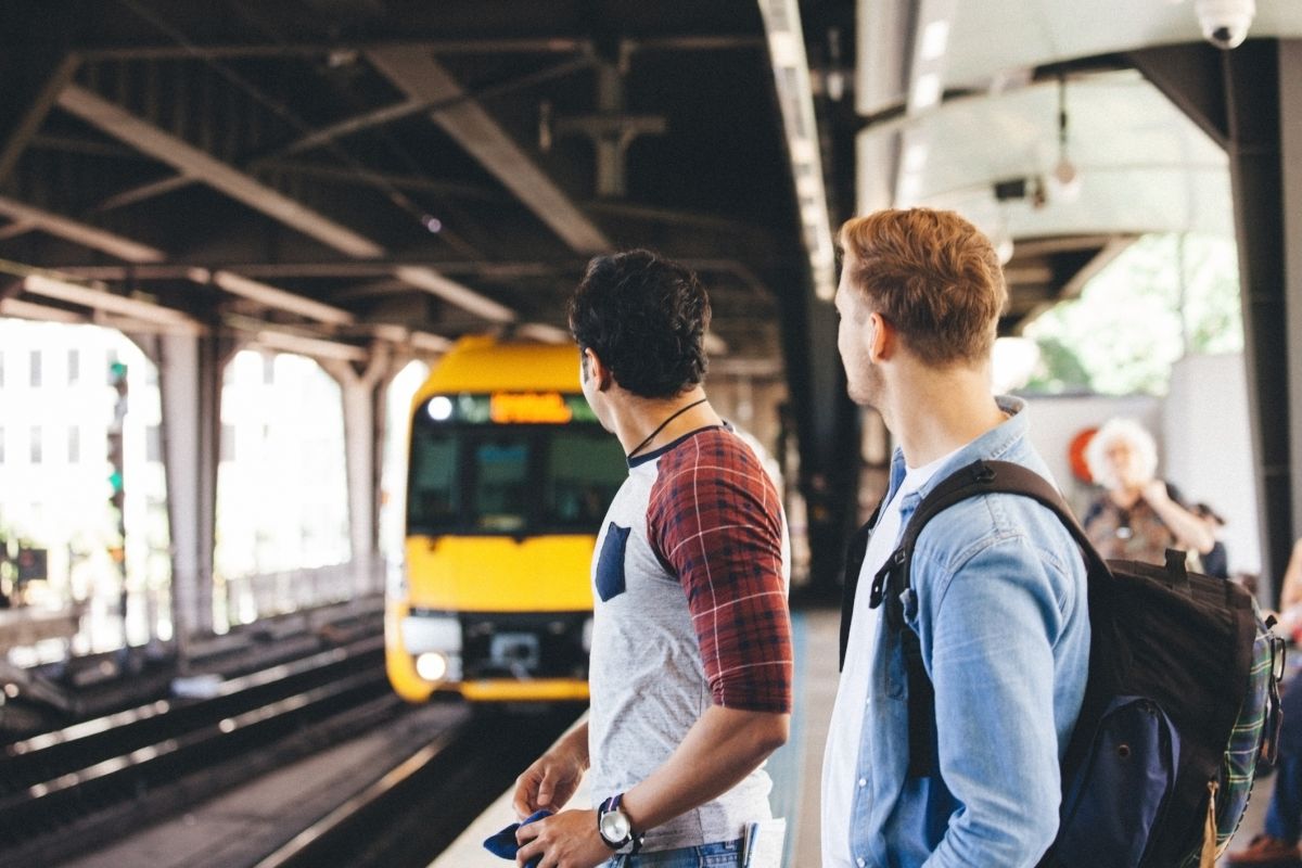 Two people looking at a train arriving at a station 