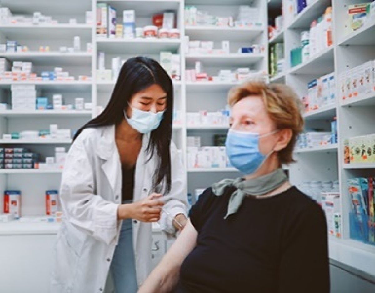 A person wearing a mask getting vaccinated in a pharmacy.