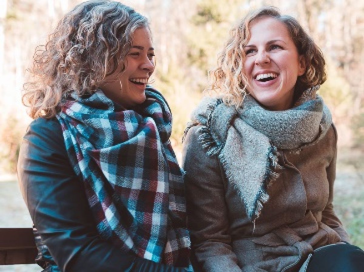 two women laughing seated on bench