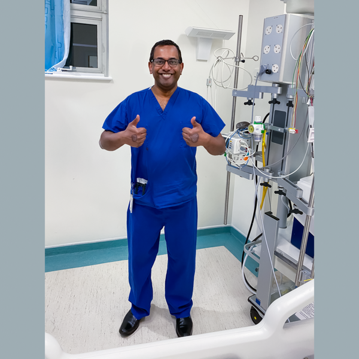 doctor in surgical scrubs gives two thumbs up