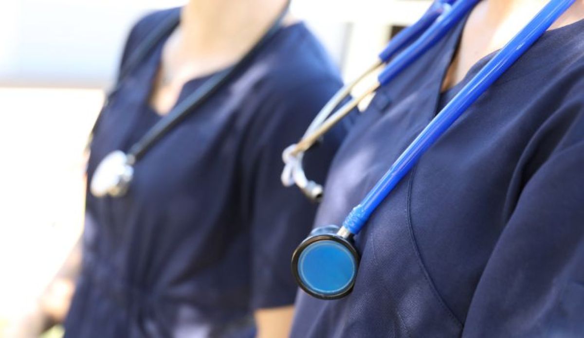 A close up of two nurses wearing stethoscopes around their necks