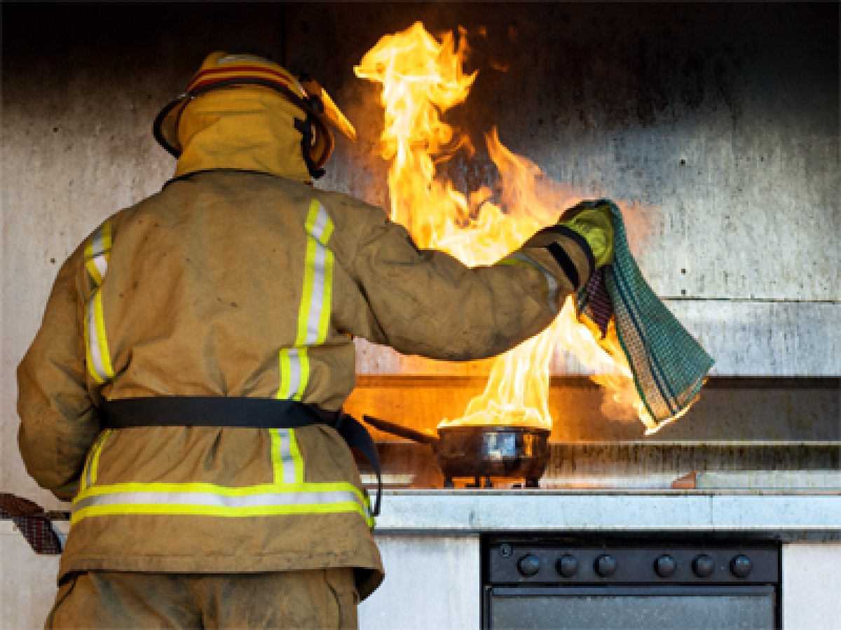 Kitchen stove fire being put out by firefighter