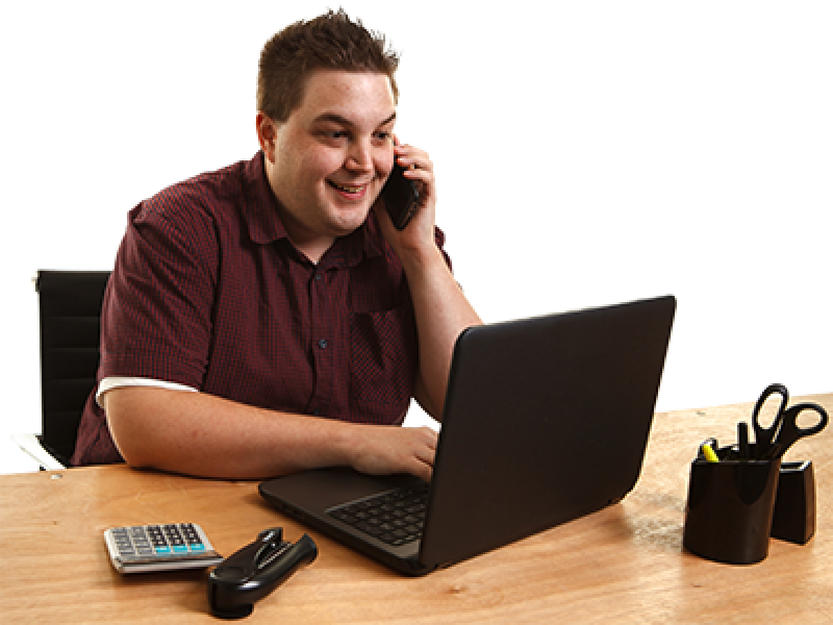 A person sitting in front of a laptop takling on the phone. 