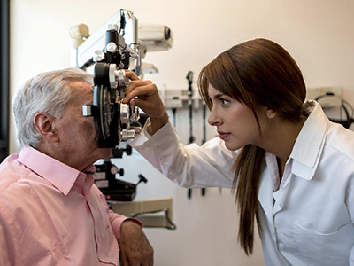 A doctor and patient in an examination room. The doctor is checking the patient's eyes.