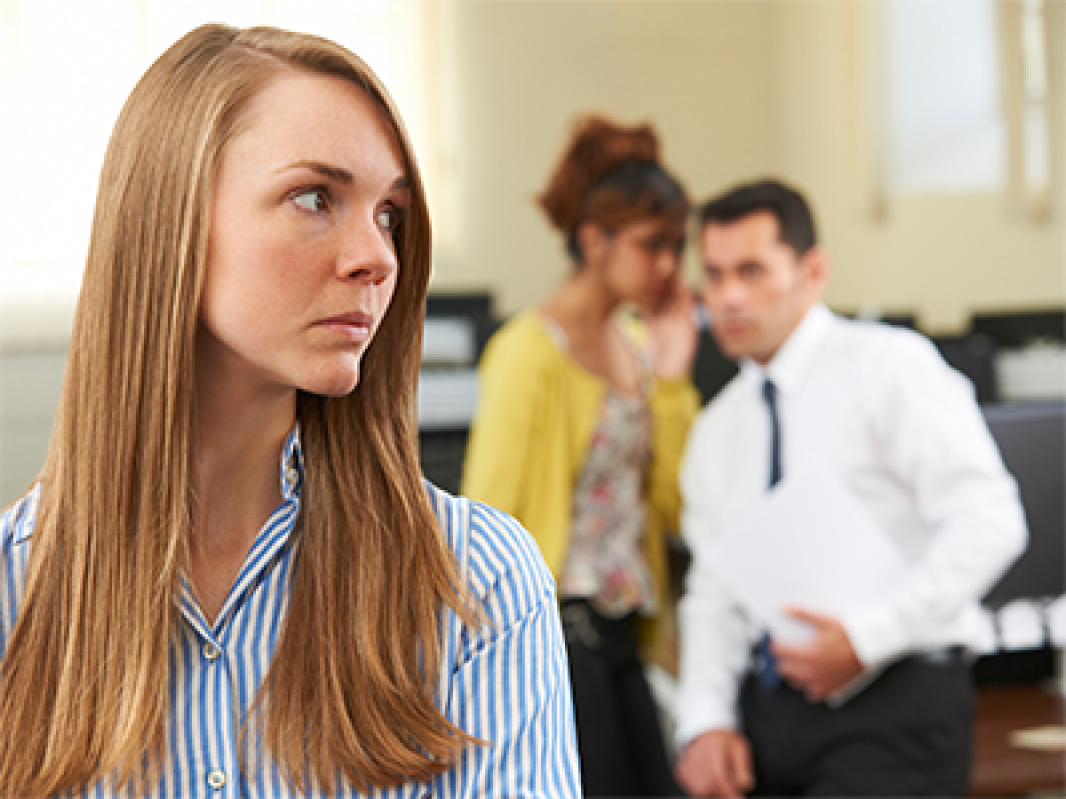 Female in foreground being bullied by colleagues gossiping in background