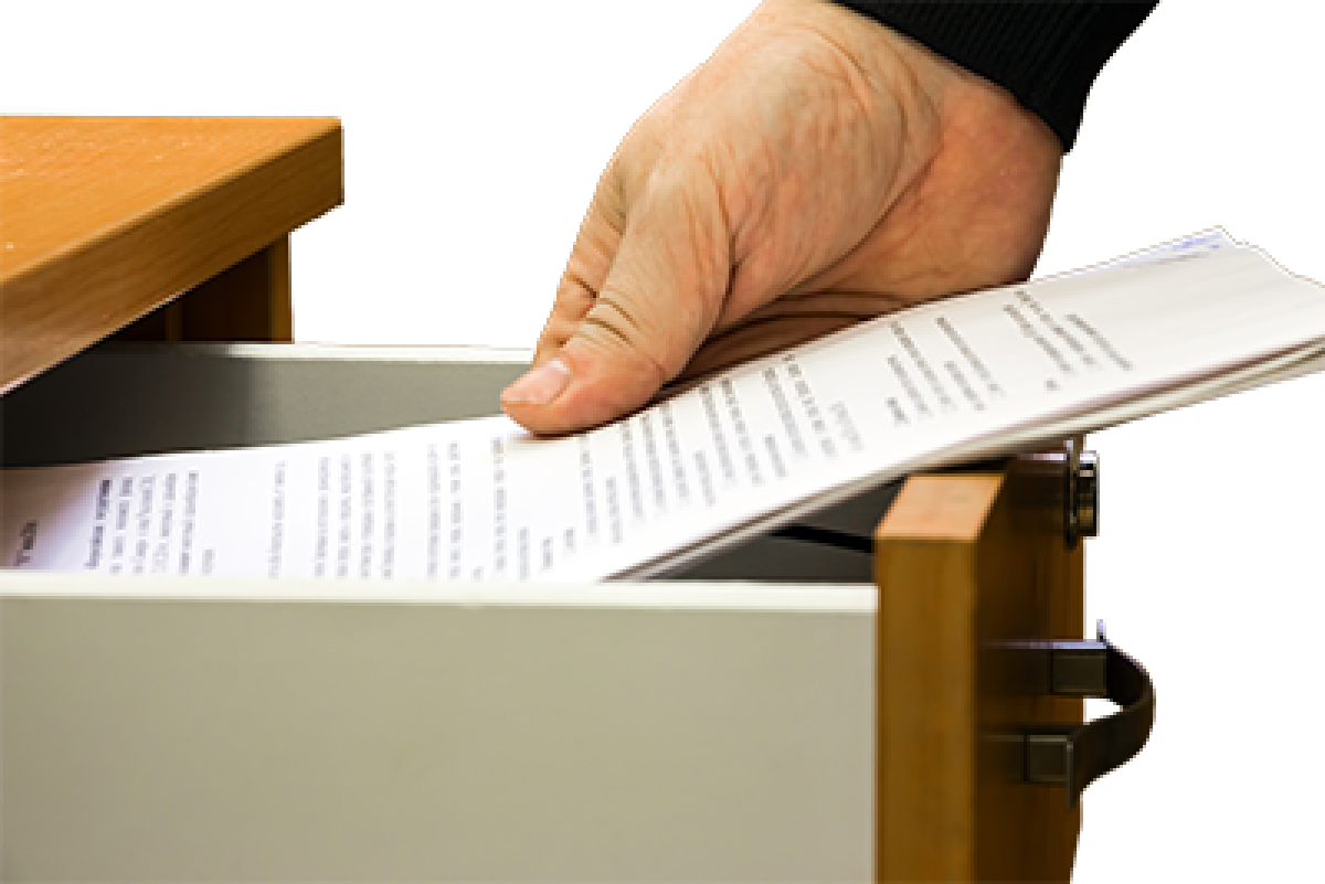 A person putting a stack of documents in a drawer.