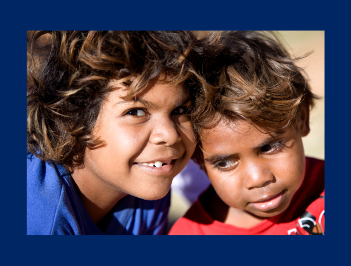 two kids with heads touching and one smiling at camera