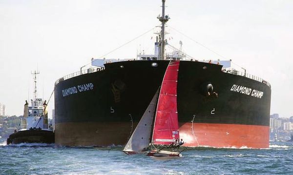 Small sailing vessel in front of large ship