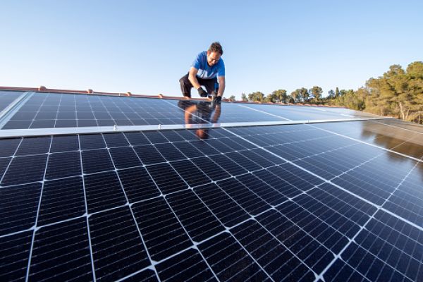 Man working on solar panels on roof