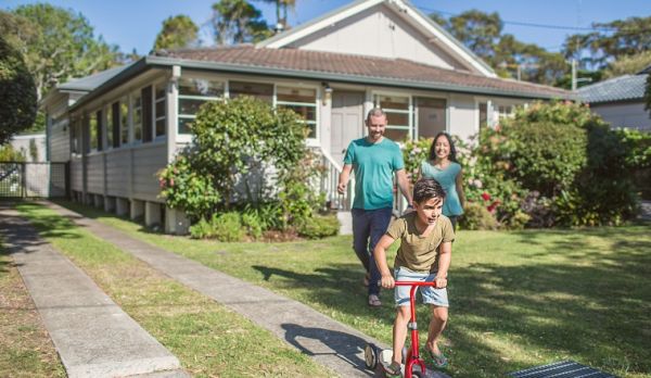 Couple with child standing on lawn in front of new home buyer