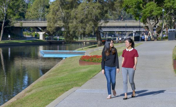 Two women walking along river in the sun.