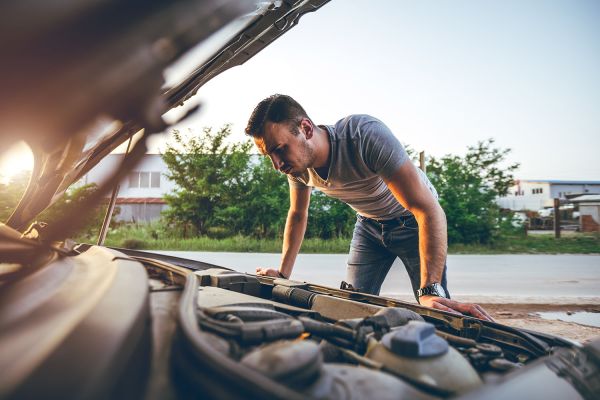 Man looking under the bonnet of a car inspecting the engine