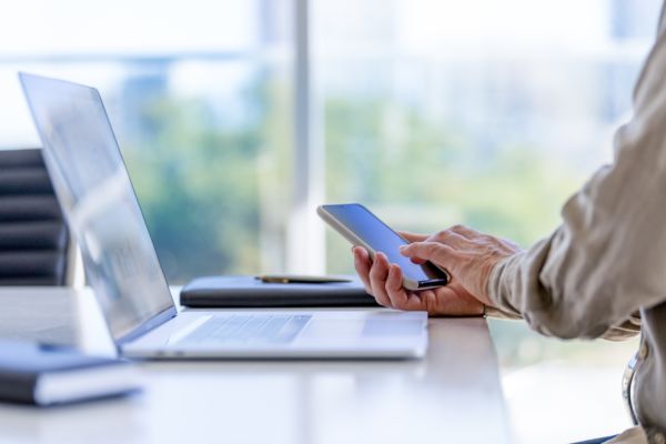 Man holding phone in fromt of a laptop