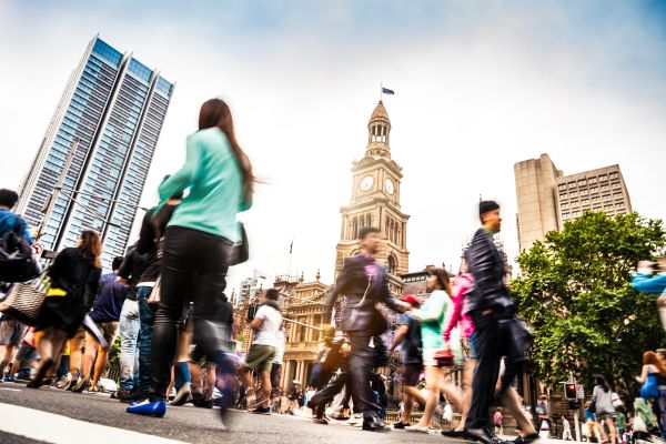 A low angle image with many workers walking out the front of a building in Sydney CBD.