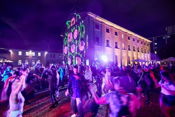 A crowd dancing outside a brightly lit building at nighttime