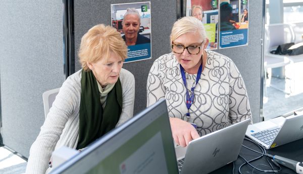 Two Justice Health NSW staff working on laptops