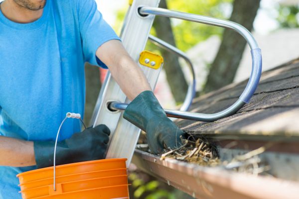 Man cleans leaves out of roof gutter