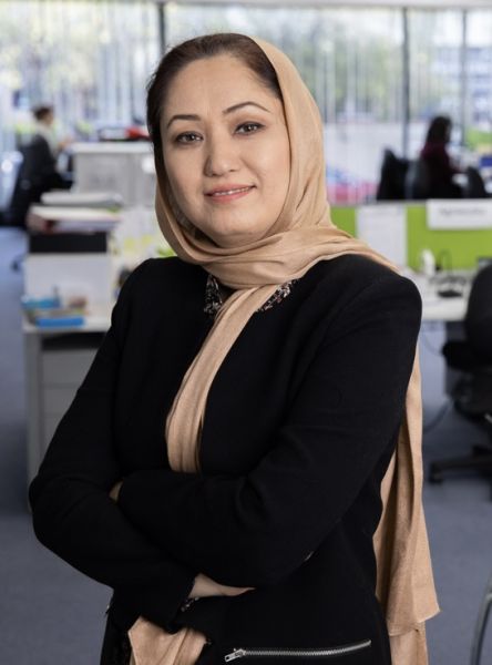 Woman in an office with her arms crossed, smiling softly