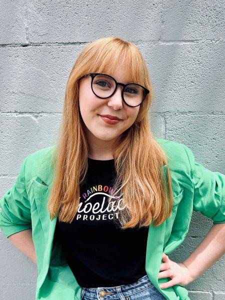 Teenage girl with glasses and a green blazer standing confidently