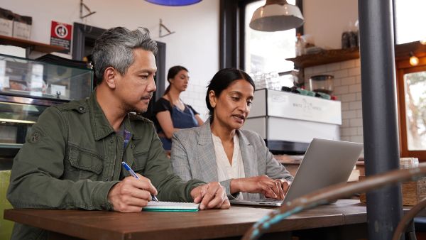 Man and woman working at a laptop together in a cafe