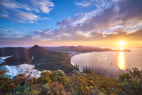 An aerial view of Mount Tomaree and the Nelson Bay shoreline during sunset in Port Stephens NSW