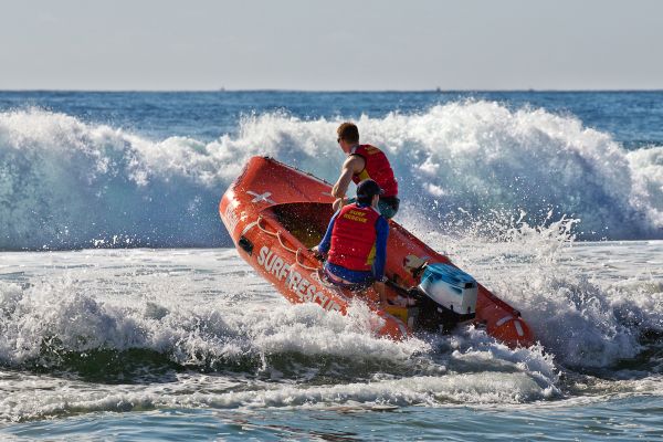 Surf lifesavers guide their dinghy out from the beach into heavy surf