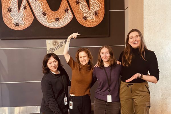 Four women stand together smiling 