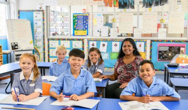 A teacher with a group of students sitting in a row in. classroom