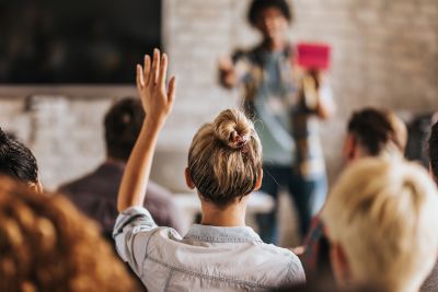 A woman raising her hand to vote in a strata meeting