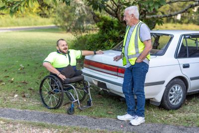 Two men in hi vis vests chat by a car