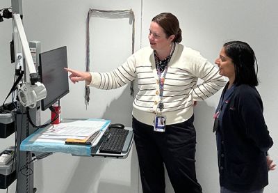 Doctor and nurse looking at a medical machine screen together in a patient treatment room.