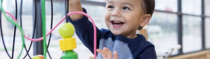 Toddler boy playing with toys in a preschool room