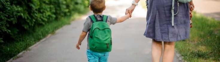 A mother walking her son down a street to a preschool