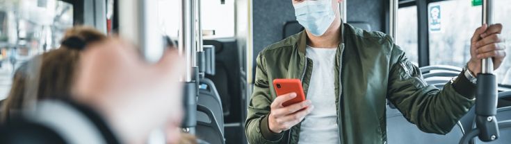 Man standing inside bus with a mobile phone