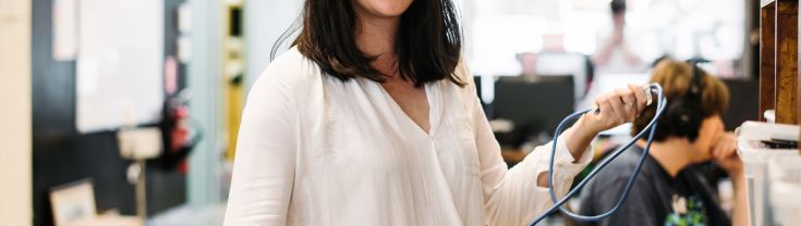 Woman smiling in office holding cords